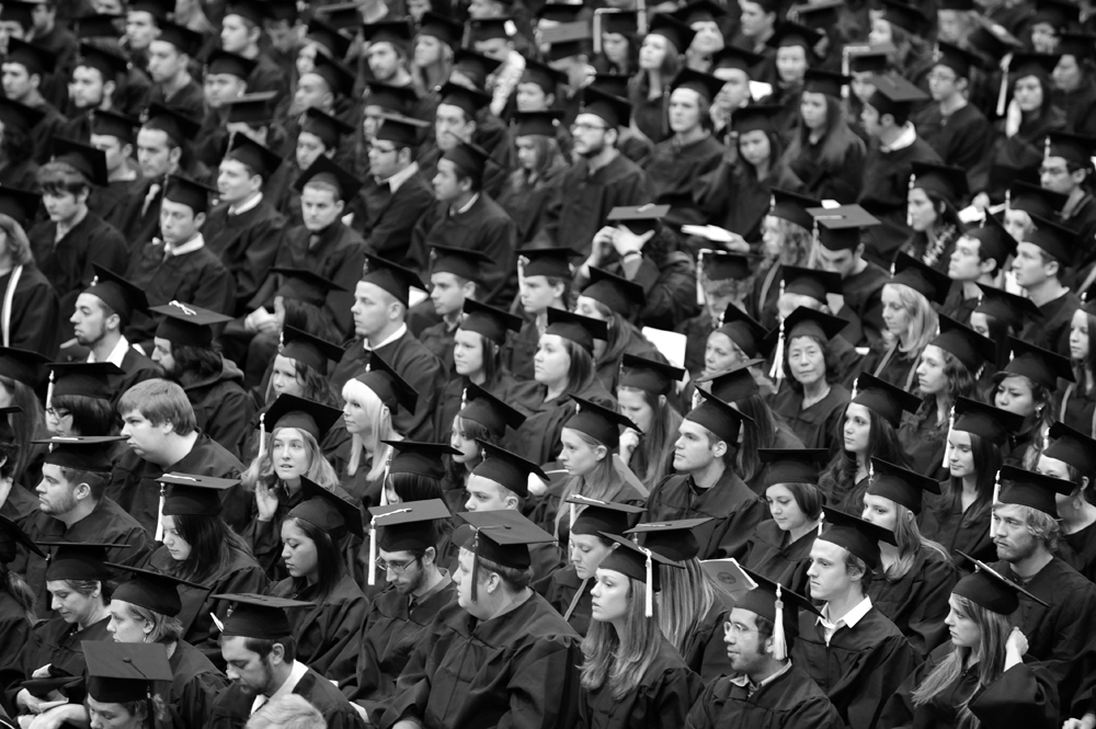 black and white photo of crowd with graduates all in cap and gowns.