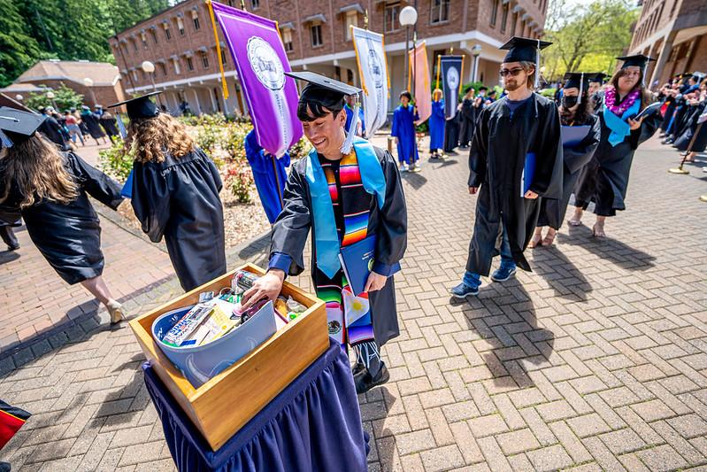 Graduate drops an item into the memory walk box during recession.