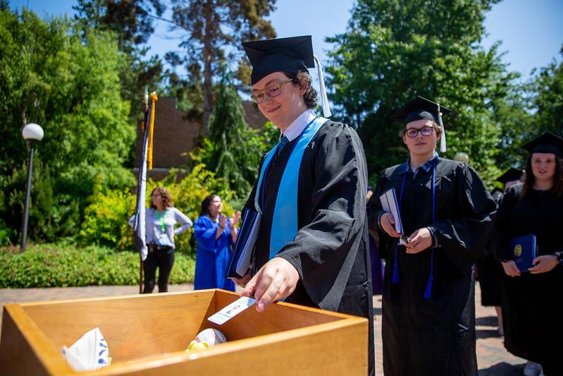 Graduate drops an item into the memory walk box during recession.