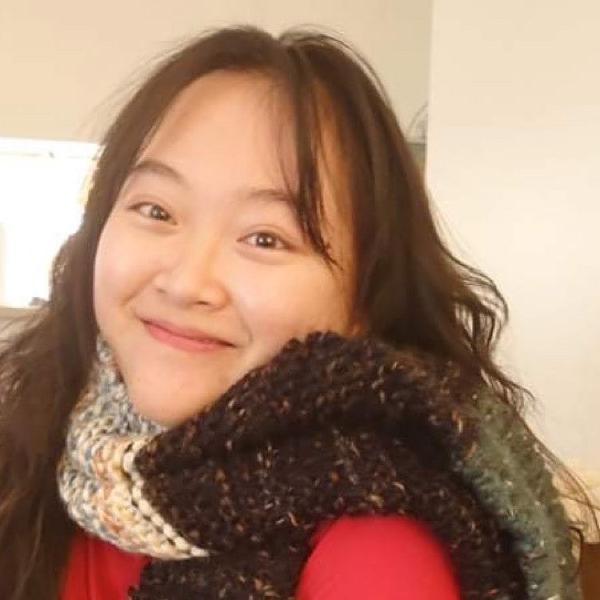 Hien Ho in a large knit scarf and red t-shirt smiling cheerfully